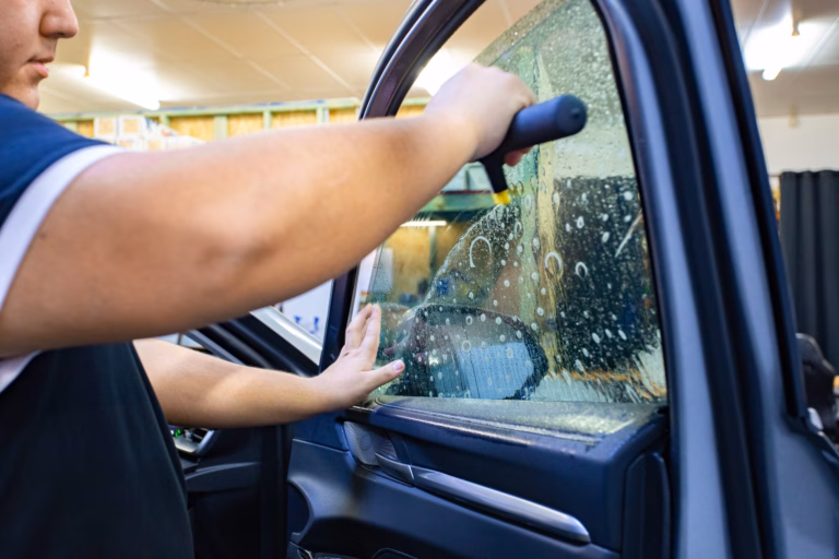 Tinting a car window with UV protection film at Tint City Bunbury